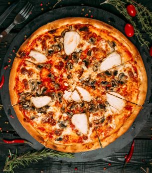 delicious-pizza-with-mushrooms-chicken-black-board-dark-wooden-table-with-herbs-tomatoes